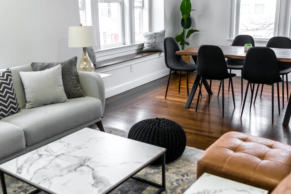 Salón preparado con sofá gris, puf de cuero y mesa de centro